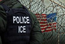 U.S. Citizen Dragged Out – ICE Faces Backlash Police officer in tactical gear standing near a barbed wire fence with an American flag in the background