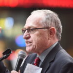 A man in a suit passionately speaking into a microphone