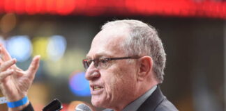A man in a suit passionately speaking into a microphone
