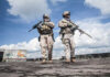 Two soldiers in tactical gear walking in an urban setting