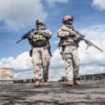 Two soldiers in tactical gear walking in an urban setting