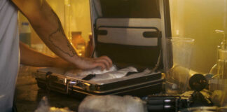 A person packing items into a suitcase in a dimly lit room