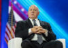 Homan Weighs Force-Feeding Detainees — ‘Hunger Strikes Won’t Change Anything’ Man in suit sitting on stage with American flag.