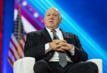 Homan Weighs Force-Feeding Detainees — ‘Hunger Strikes Won’t Change Anything’ Man in suit sitting on stage with American flag.
