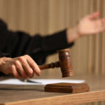 Judge's hand striking a wooden gavel on a block