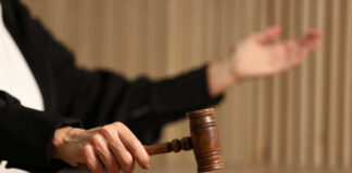 Judge's hand striking a wooden gavel on a block