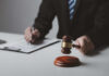 Brooklyn Judge’s Shocking $5M Fraud Scandal Person with gavel signing document at desk