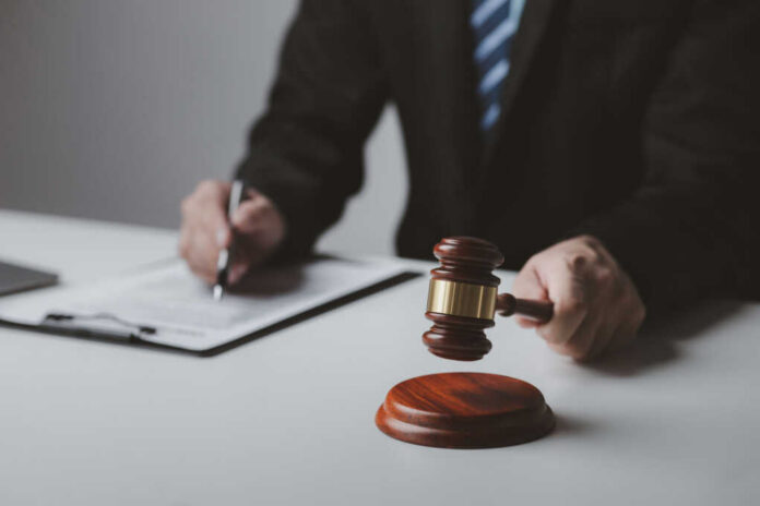 Person with gavel signing document at desk