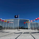 Russia Regroups—NATO Caught Napping NATO headquarters with member flags in front under a clear blue sky