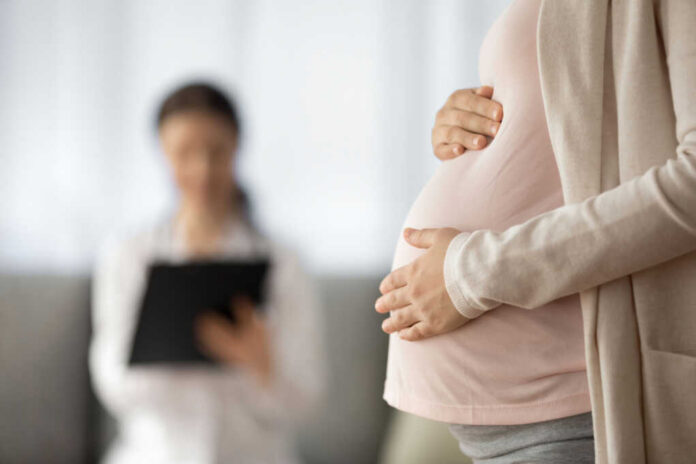 pregnant-woman2043915227jpg Pregnant person holding their belly during a medical visit