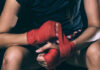Athlete wrapping hands with red boxing tape
