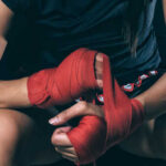 Athlete wrapping hands with red boxing tape