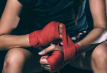 Athlete wrapping hands with red boxing tape