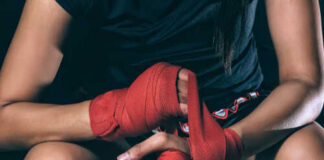 Athlete wrapping hands with red boxing tape