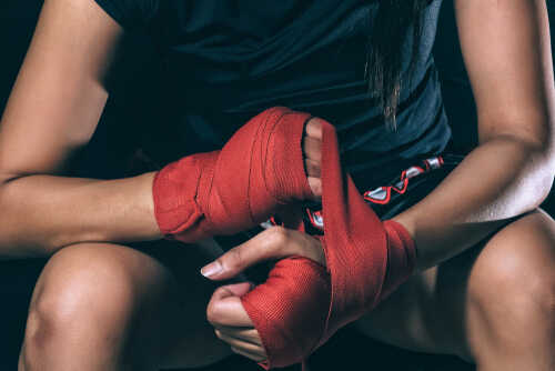Athlete wrapping hands with red boxing tape