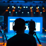 Tax War Guts LA—Jersey Rakes In Productions Cameramen preparing for a video shoot on a brightly lit stage
