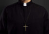 Vatican Report IGNITES Clergy Rebellion—Church Fractures Clerical shirt with a cross necklace against a dark background