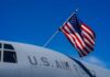 U.S. Air Force aircraft with an American flag waving against a blue sky