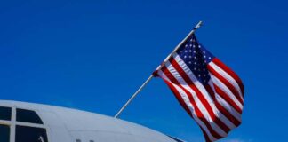U.S. Air Force aircraft with an American flag waving against a blue sky