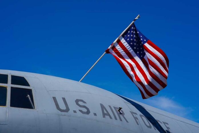 U.S. Air Force aircraft with an American flag waving against a blue sky