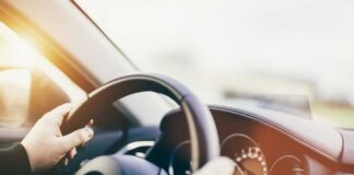 Hands gripping a steering wheel inside a car