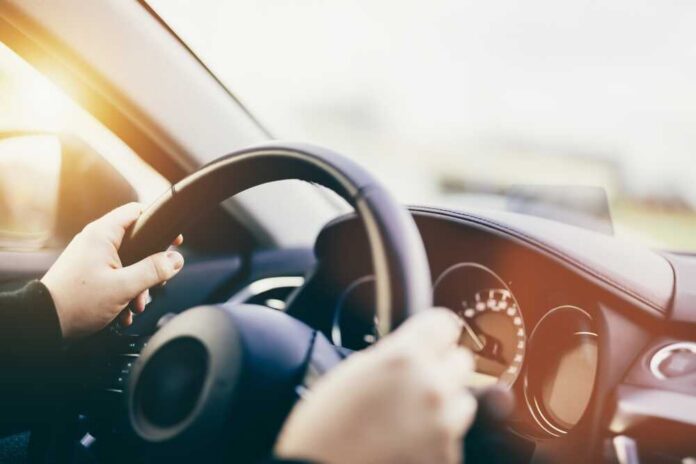 Driver,Hands,On,Steering,Wheel,Driving,A,Car.,Transportation Hands gripping a steering wheel inside a car