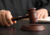 WOMAN Ticketed for NONEXISTENT Hand — CASE DISMISSED A judge's hand holding a gavel above a wooden block