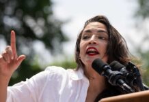 A woman passionately speaking at a podium with microphones
