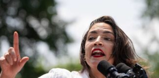 A woman passionately speaking at a podium with microphones