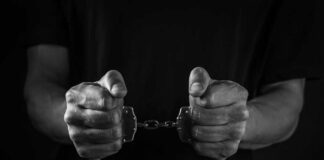 Hands holding handcuffs in a black and white image