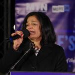 A woman speaking into a microphone at an outdoor event