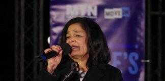 A woman speaking into a microphone at an outdoor event