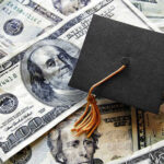 A graduation cap placed on a pile of U.S. dollar bills