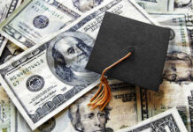 A graduation cap placed on a pile of U.S. dollar bills