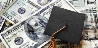 A graduation cap placed on a pile of U.S. dollar bills