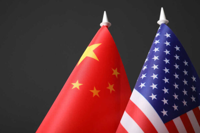 us-china-593900280 Chinese and American flags against dark background