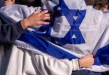 Israel Bombs—Then Aids—Christian Villages? People holding an Israeli flag together, showcasing unity and cultural pride