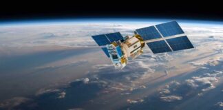 A satellite equipped with solar panels orbiting above the Earth, surrounded by clouds