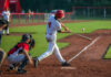 Baseball batter in white uniform hitting a pitched ball