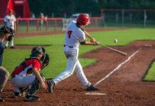 Baseball batter in white uniform hitting a pitched ball