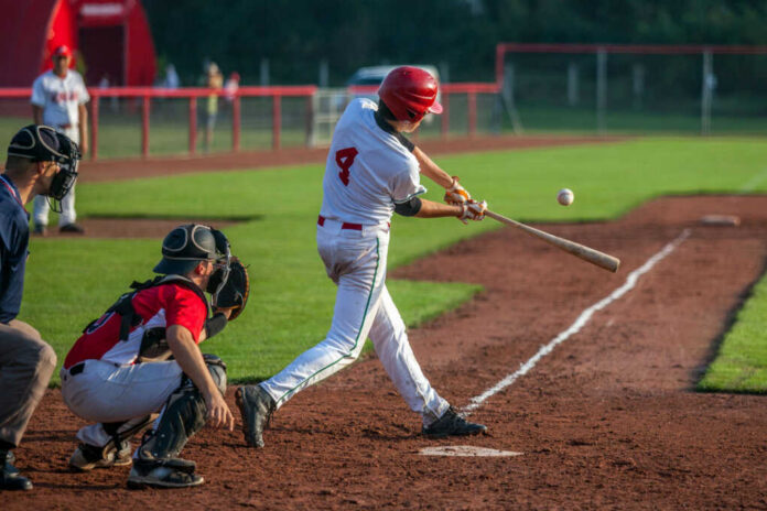 Baseball batter in white uniform hitting a pitched ball