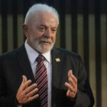 Elderly man in suit speaking with hands raised