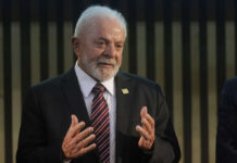 Elderly man in suit speaking with hands raised