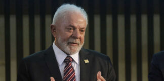 Elderly man in suit speaking with hands raised