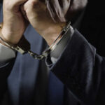 Most Wanted Fraudster Falls In Manila Businessperson in suit with hands cuffed together