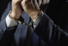 Most Wanted Fraudster Falls In Manila Businessperson in suit with hands cuffed together