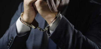 Businessperson in suit with hands cuffed together