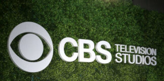 CBS Television Studios logo on green hedge backdrop