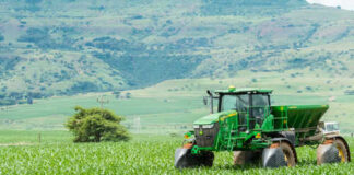 Green tractor working on a lush field landscape