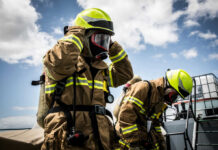 Inmates On The Frontlines — California Cashes In On Captive Crews Firefighters in protective gear standing outside cloudy sky